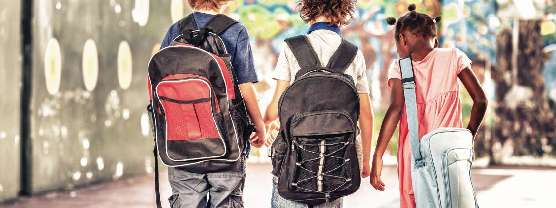 Tre skolelever går omkring med ryggsäckar. 