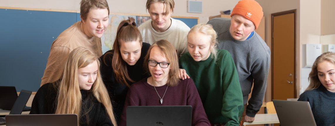 Ryhmä lukio-opiskelijoita tutkivat yhtä tietokonetta. 