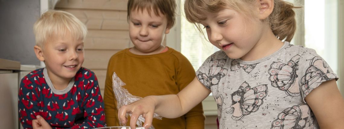 Päiväkoti-ikäiset lapset kokeilevat, miten pyyhekumi kelluu veden pinnalla. 