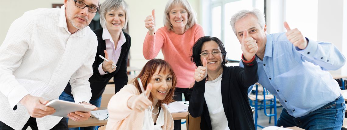 Ryhmä aikuisopiskelijoita näyttää peukkua